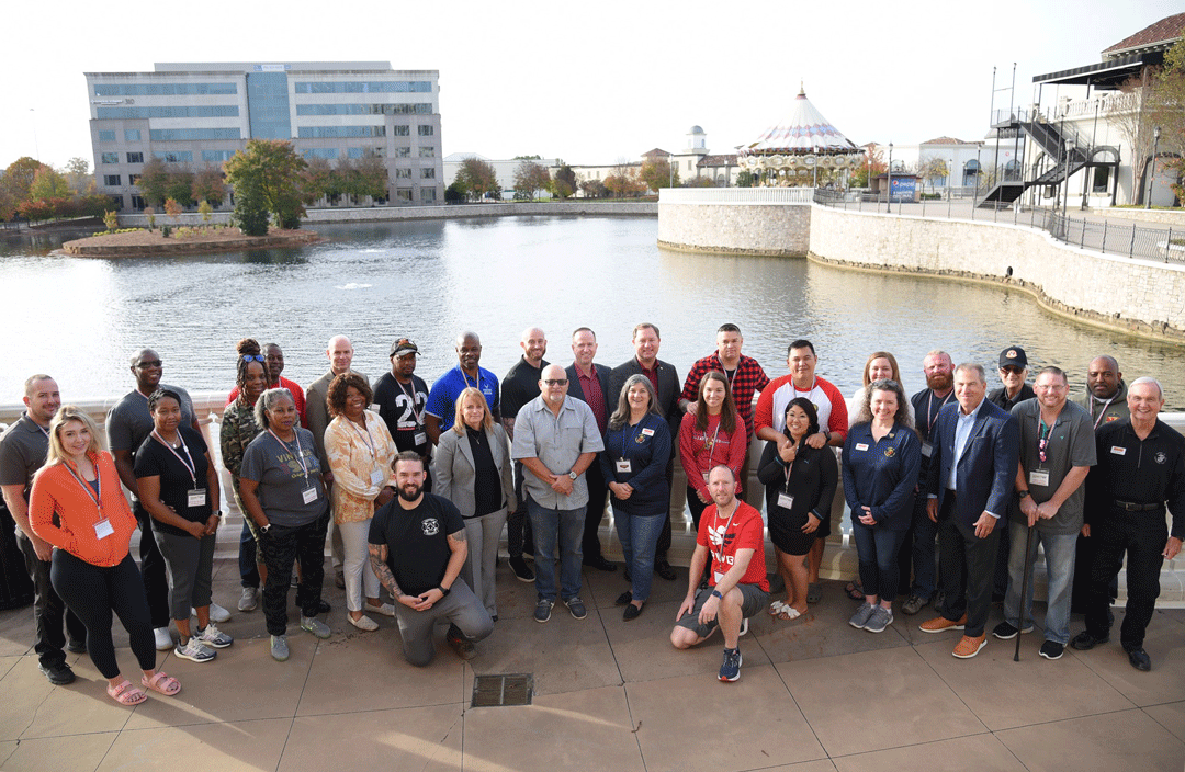 Community-Partners-Breakfast-2022: Large group photo outside with the Bridge Street pond in the background, and a large corporate building.