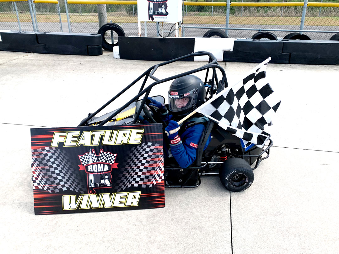 Semper Fi Racer Wins - youth driver sitting in vehicle holding checkered flag with Feature Winner sign